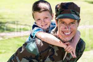 Happy soldier giving piggyback to his son