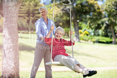 Senior man pushing his partner on swing