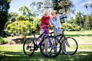 Senior couple standing with bicycle in park