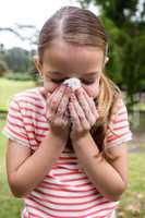 Sick girl sneezing in the park