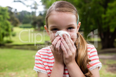 Sick girl sneezing in the park