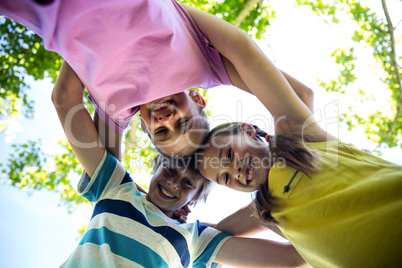 Portrait of happy children forming a huddle in park