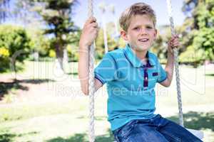 Boy sitting on a swing in the park