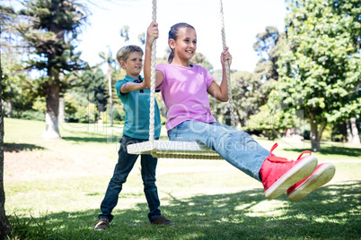 Boy pushing his sister on swing