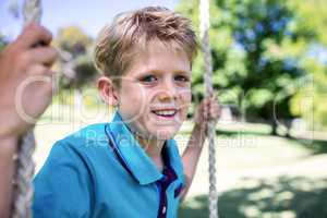 Boy sitting on a swing in the park
