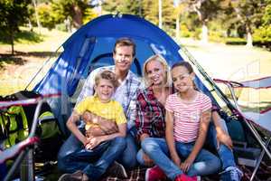 Happy family sitting in front of a tent
