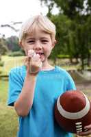 Boy with an american football using an asthma inhaler