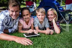 Portrait of a family lying on grass and using digital tablet