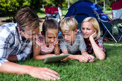 Family lying on grass and using digital tablet