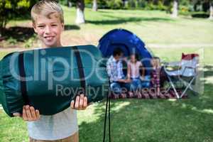 Portrait of a boy holding a camping bag