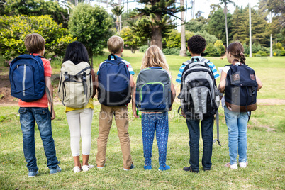 Rear view of children with bags standing together