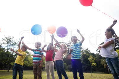 Happy children playing with balloons in the park