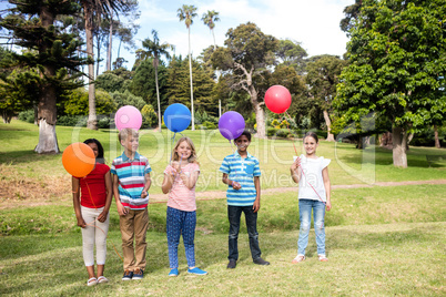 Children standing with balloons in the park