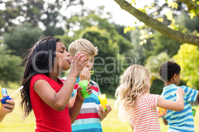 Children blowing bubbles wand in the park