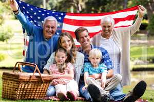 Multi-generation family holding american flag in the park