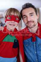 Portrait of father and son pretending to be superhero in living
