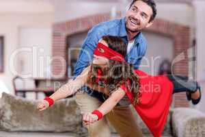 Father and daughter pretending to be superhero in living room
