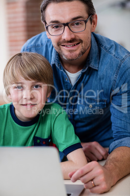 Portrait of father and son using laptop in kitchen