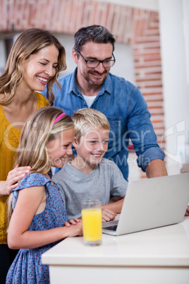 Parents and kids using laptop in kitchen Parents and kids using laptop in kitchen