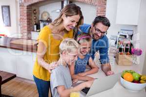 Parents and kids using laptop in kitchen