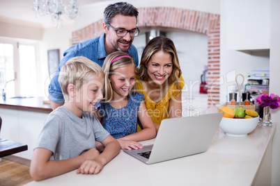 Parents and kids using laptop in kitchen