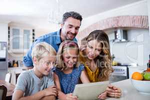 Parents and kids using digital tablet in kitchen