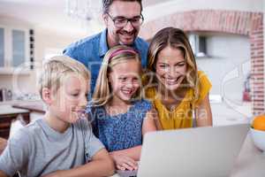 Parents and kids using laptop in kitchen