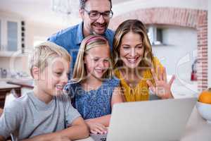 Parents and kids using laptop in kitchen