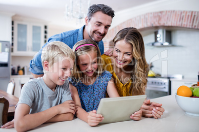 Parents and kids using digital tablet in kitchen