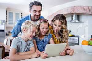 Parents and kids using digital tablet in kitchen