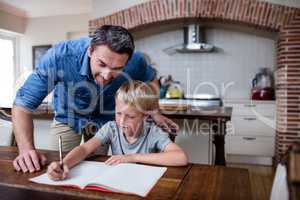 Father helping son with his homework in kitchen