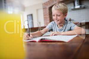 Smiling boy doing homework in kitchen