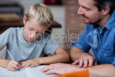 Father helping son with his homework in kitchen