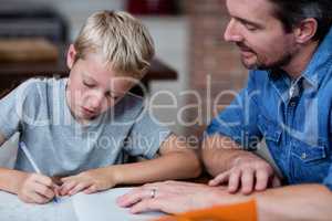 Father helping son with his homework in kitchen