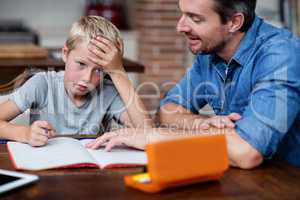 Father helping son with his homework in kitchen