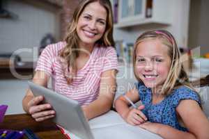 Mother using a digital tablet while helping daughter with her ho