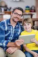 Father and son using digital tablet in living room