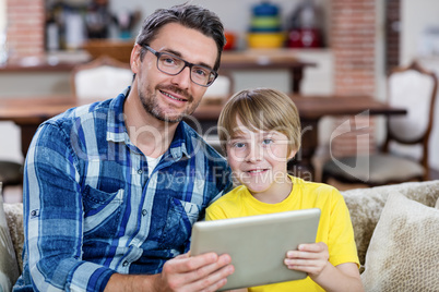 Portrait of father and son using digital tablet in living room