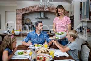 Woman serving food to her family in the kitchen