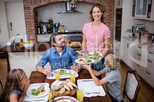 Woman serving food to her family in the kitchen