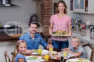 Woman serving food to her family in the kitchen