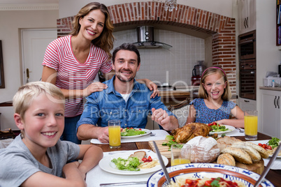 Portrait of happy family having meal in kitchen