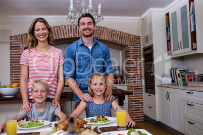 Portrait of happy family having meal in kitchen