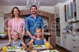 Portrait of happy family having meal in kitchen