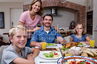 Portrait of happy family having meal in kitchen