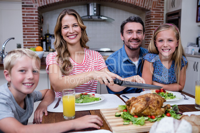 Woman cutting roasted turkey while having meal with his family