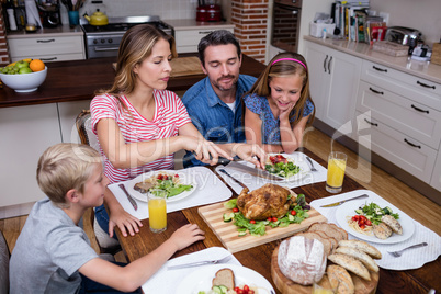 Woman cutting roasted turkey while having meal with his family