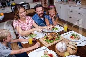 Woman cutting roasted turkey while having meal with his family