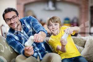 Father and son playing video game on sofa