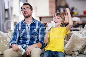 Father and son playing video game on sofa